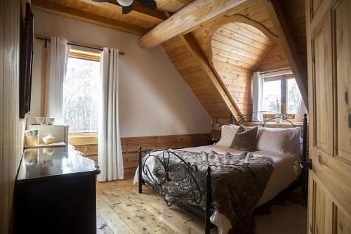 - une chambre avec un lit et un plafond en bois dans l'établissement Hébergement "La Maison en Bois Rond", à Sainte-Marie