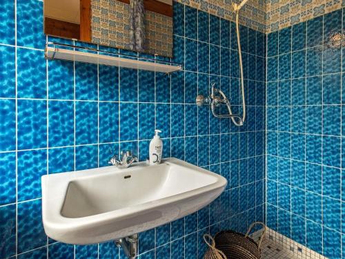 Baño de azulejos azules con lavabo y espejo en Holiday home Hesselager VII, en Hesselager