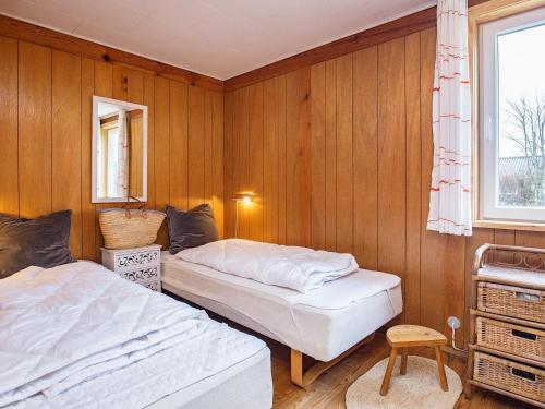 two beds in a room with wooden walls and a window at Holiday home Hesselager VII in Hesselager