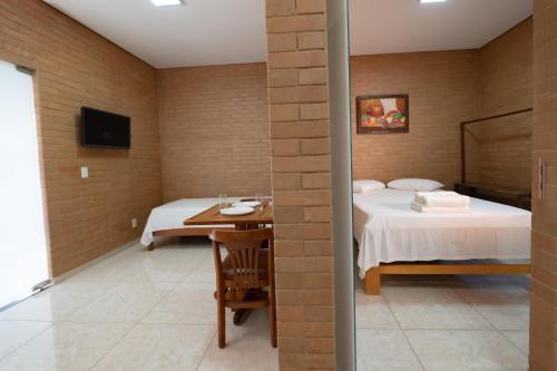 um quarto com uma cama, uma mesa e uma televisão em Flats Oliveira em Pirenópolis
