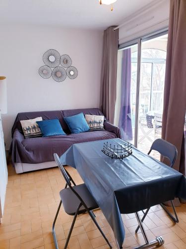 un salon avec un canapé et une table avec des chaises dans l'établissement JEAN BART I Joli T2 cabine proche plage Richelieu Cap d'Agde, au Cap d'Agde