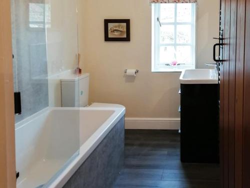 a bathroom with a large bath tub and a sink at The Cottage in Sinnington