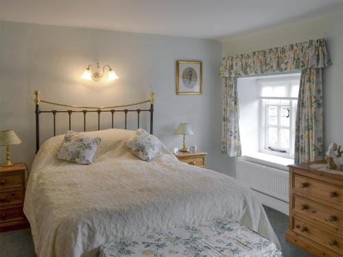 1 dormitorio con 1 cama con 2 almohadas y ventana en The Cottage, en Sinnington