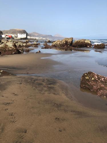 a sandy beach with rocks and the ocean at Nueve Pies Surf casita in Las Palmas de Gran Canaria