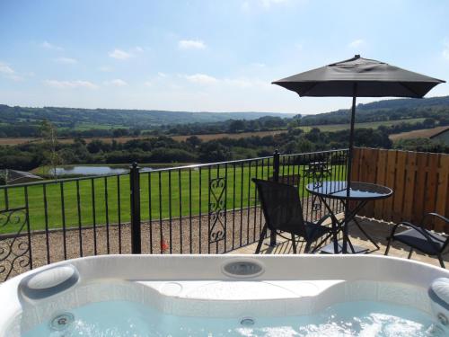 a bath tub with a table and an umbrella at Willow cottage, romantic retreat near Honiton Devon in Honiton