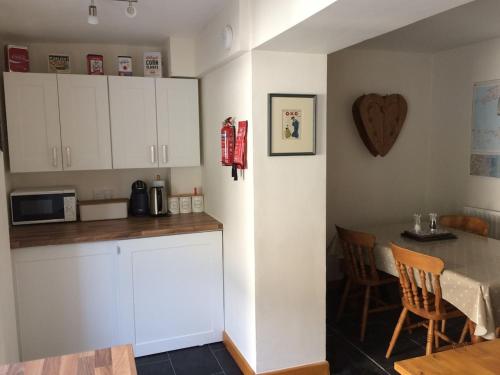 a kitchen with white cabinets and a table and a tableablish at Seasalt Cottage - Modernised traditional cottage, Sleeps 5,short walk to beaches, town, amenities in Pembrokeshire