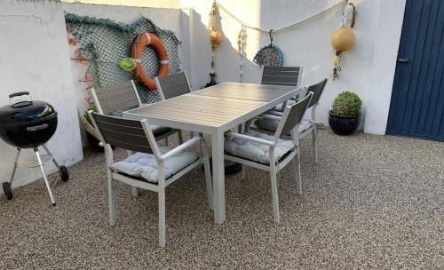 a table with chairs and a grill in a room at Seasalt Cottage - Modernised traditional cottage, Sleeps 5,short walk to beaches, town, amenities in Pembrokeshire