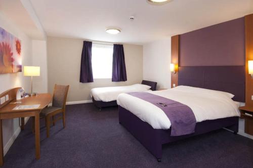 a hotel room with a bed, chair, and table at Premier Inn Manchester Airport Runger Lane North in Hale
