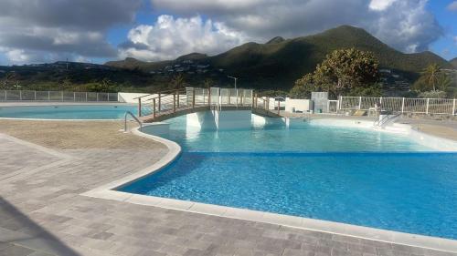a large swimming pool with mountains in the background at Orient Bay Beach Studio in Orient Bay