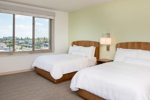 two beds in a hotel room with a window at Element Scottsdale at SkySong in Scottsdale