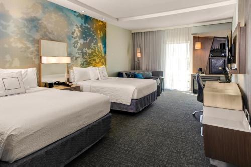 a hotel room with two beds and a television at Courtyard by Marriott New Orleans Westbank/Gretna in Gretna