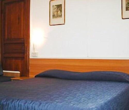 a bedroom with a blue bed with a wooden headboard at Hotel Fernanda in Rapallo