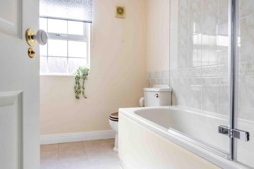 a white bathroom with a tub and a toilet at Spacious 5 bedroom house in quiet cul-de-sac in Shrewsbury