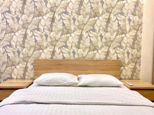 ein Bett mit zwei Kissen vor einer Wand in der Unterkunft 2-кімн Сучасні апартаменти у центрі міста in Poltawa