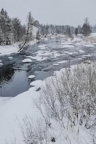 a river covered in snow with ice and trees at Villa Fregn in Ljørdal