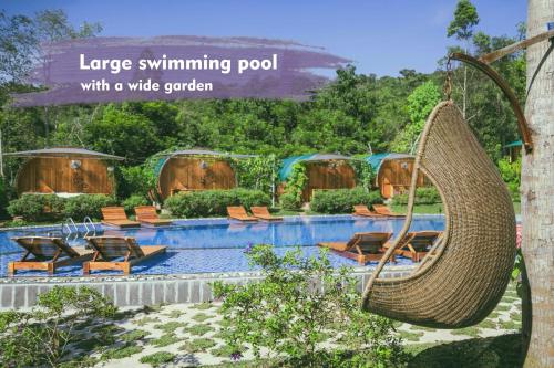 a large swimming pool with a wide garden with a wicker swing at Phu Quoc Valley Sen Bungalow in Phu Quoc
