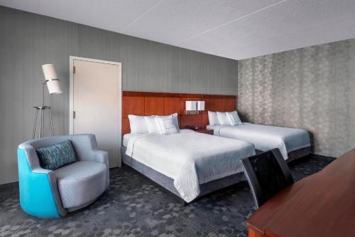 a hotel room with two beds and a chair at Courtyard Newark Liberty International Airport in Newark