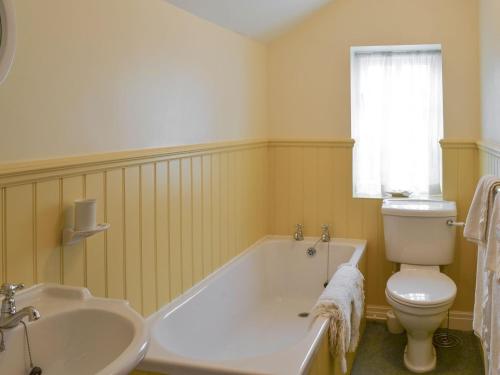 a bathroom with a tub and a toilet and a sink at Lilac Cottage in Sinnington