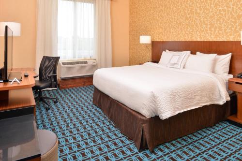 Fairfield Inn & Suites by Marriott Warrensburg في ارنسبورغ: غرفة فندقية فيها سرير ومكتب وتلفزيون