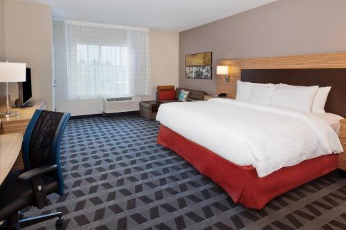 ein Hotelzimmer mit einem großen Bett und einem Stuhl in der Unterkunft TownePlace Suites by Marriott Montgomery EastChase in Montgomery