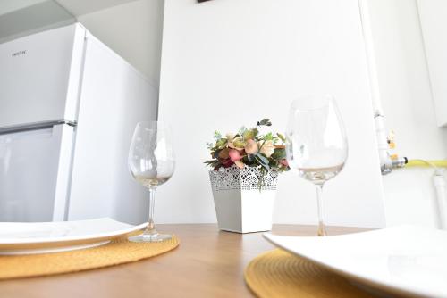 dos copas de vino sentadas en una mesa con una planta en Mall Luxury VI Apartment, en Bacău