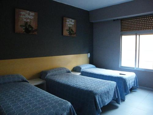 Habitación de hotel con 2 camas y ventana en Pensión Corona, en Zaragoza