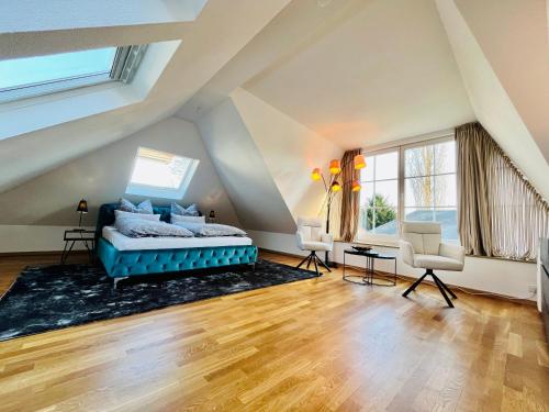 a attic bedroom with a blue bed and two chairs at Villa am Park Apartment in Dresden