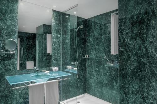 a green bathroom with a sink and a shower at AC Hotel Guadalajara by Marriott, Spain in Guadalajara