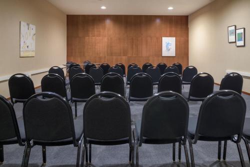 a conference room with black chairs in front of a wooden wall at AC Hotel Guadalajara by Marriott, Spain in Guadalajara