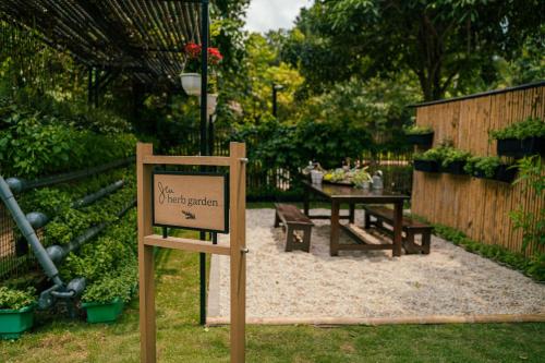 a sign in a garden with a table and benches at JW Marriott Hotel Hanoi in Hanoi