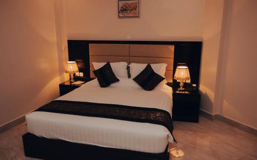a bedroom with a large white bed with two lamps at Madras Hotel and Apartments in Kigali