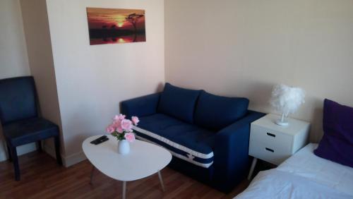 a living room with a blue couch and a table at Petite maison indépendante avec terrasse privée in Montmorillon