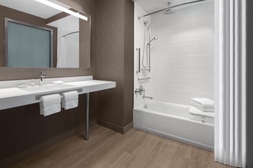 a bathroom with a sink and a tub and a mirror at AC Hotel by Marriott Fort Lauderdale Sawgrass Mills Sunrise in Sunrise