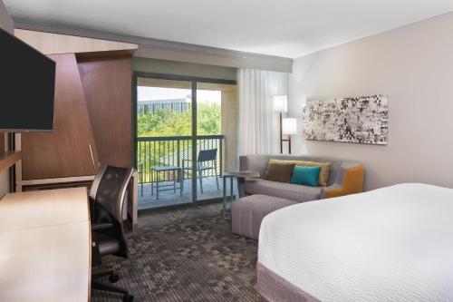 a hotel room with a bed and a chair and a desk at Courtyard Lafayette Airport in Lafayette