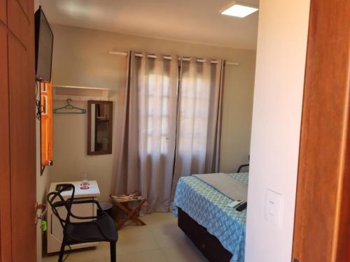 um quarto com uma cama, uma cadeira e uma janela em Suíte na vila de Praia do Forte na Praia do Forte