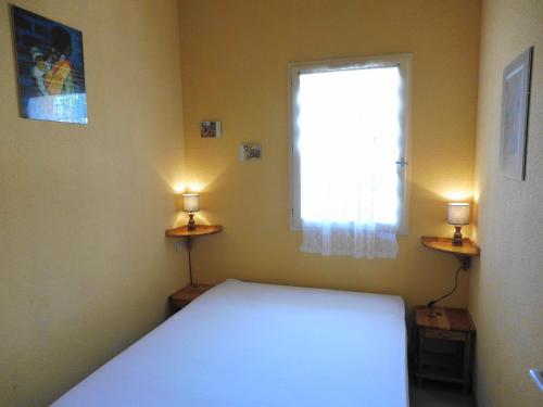 1 dormitorio con 1 cama y una ventana con 2 luces en MAISONS DU GOLF Joli T3 villa mitoyenne proche plage Richelieu Cap d'Agde, en Cap d'Agde