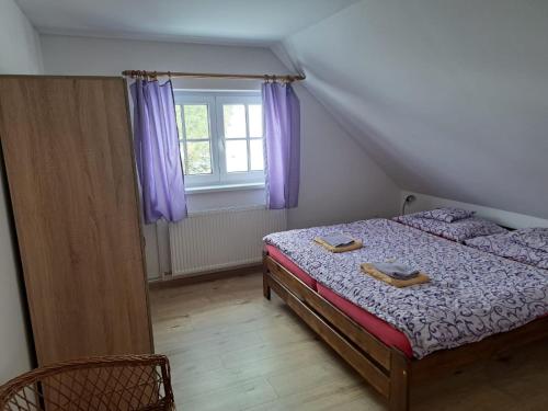Schlafzimmer mit einem Bett und einem Fenster mit lila Vorhängen in der Unterkunft Penzion Richard in Bělá pod Pradědem