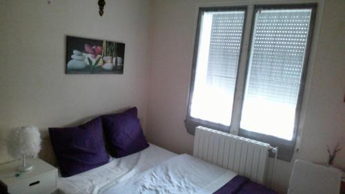 a bedroom with a bed with purple pillows and a window at Petite maison indépendante avec terrasse privée in Montmorillon