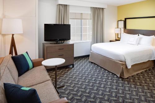 ein Hotelzimmer mit einem Bett, einem Sofa und einem TV in der Unterkunft Residence Inn by Marriott Tysons in Tysons Corner