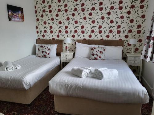a room with two beds and a floral wallpaper at Eastmount Hall Hotel in Shanklin