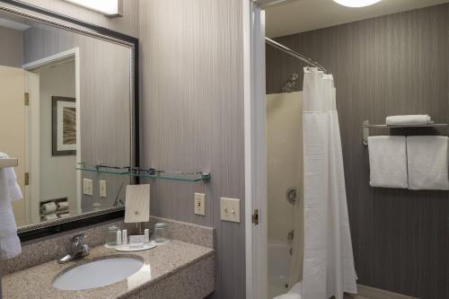 a bathroom with a sink and a mirror and a shower at Courtyard by Marriott Vacaville in Vacaville