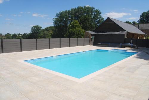 a swimming pool in a backyard with a fence at Gites Les Coudreaux in Saint-Siméon