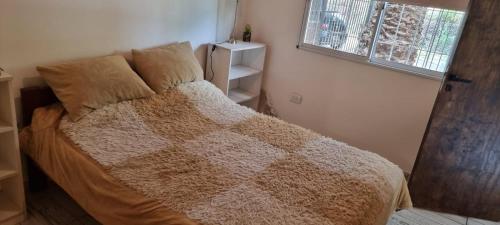 1 dormitorio con 1 cama con manta marrón y ventana en Departamento Costa Paz en Villa Carlos Paz