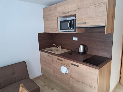 a small kitchen with a sink and a microwave at Penzion Richard in Bělá pod Pradědem
