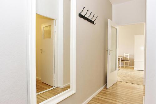 BearlinCity Apartments - City Center West في برلين: ممر مع مرآة في غرفة بيضاء