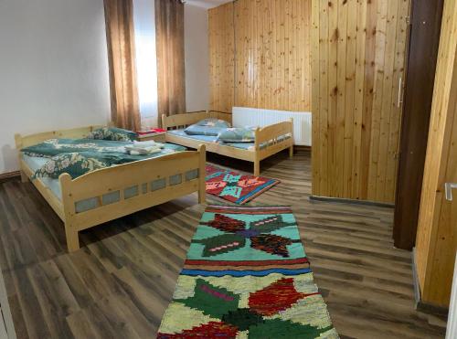 a room with two beds and a rug on the floor at Cabana Elena in Gîrda de Sus