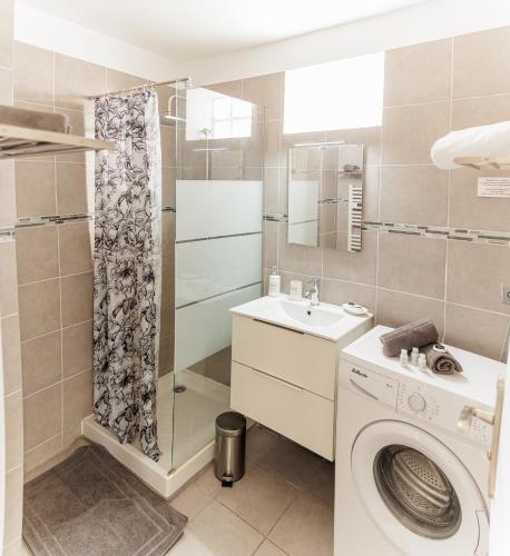une salle de bain avec une machine à laver et un lavabo dans l'établissement Plage des catalans/vieux port, à Marseille