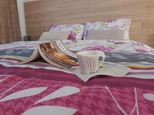 a bed with a book and a cup on it at Apartman Cristal LUX in Trebinje