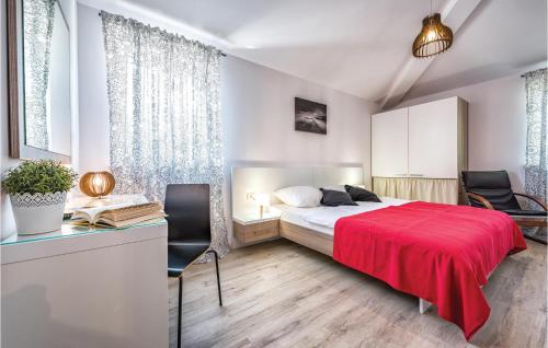 Cette chambre comprend un lit avec une couverture rouge et un bureau. dans l'établissement Beautiful Home In Kunj With Wifi, à Kunj