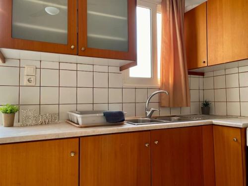 a kitchen with wooden cabinets and a sink and a window at Elgreco Apartment, with nice view, in Kos Town "12" in Kos Town